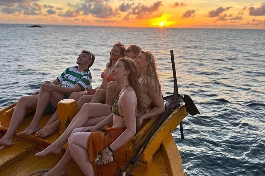 A group of people on a boat at sunset. 1