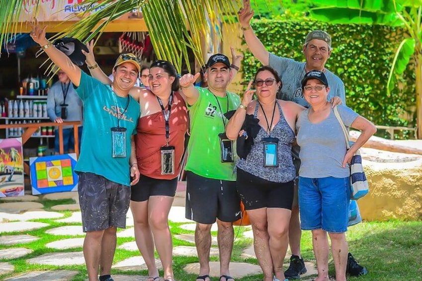 A group of people posing for a photo in a tropical setting with palm trees and a colorful play area in the background. 3