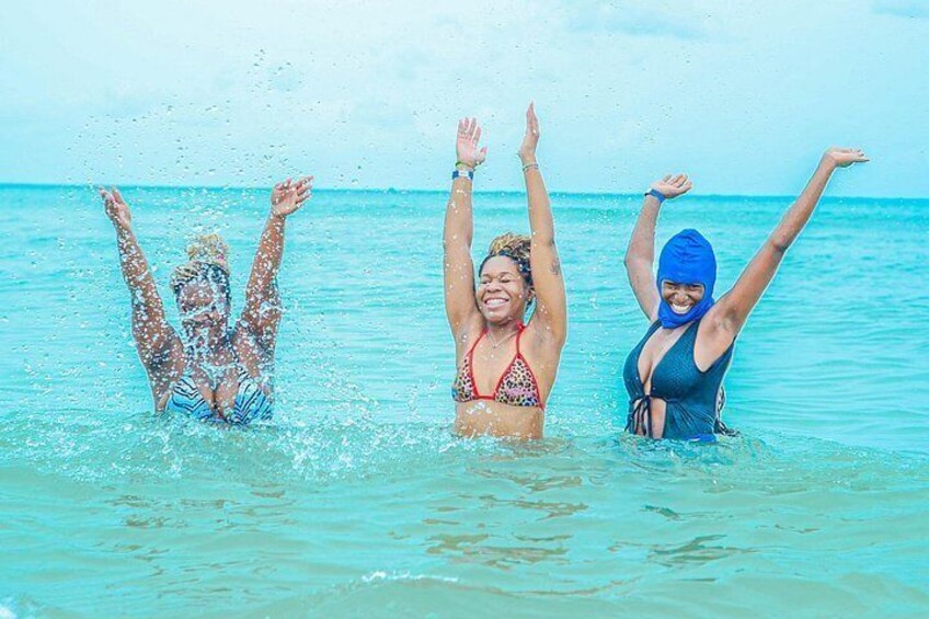 Three people in the ocean water, with one person splashing water. 4