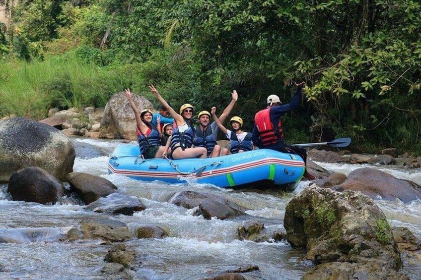 A group of people rafting on a blue inflatable raft through a rocky river. 1