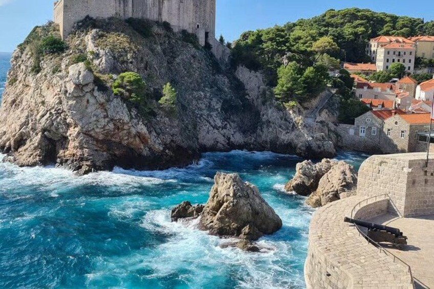 Une ville côtière qui se distingue par une imposante tour en pierre, un littoral rocheux et des bâtiments aux toits rouges. 5