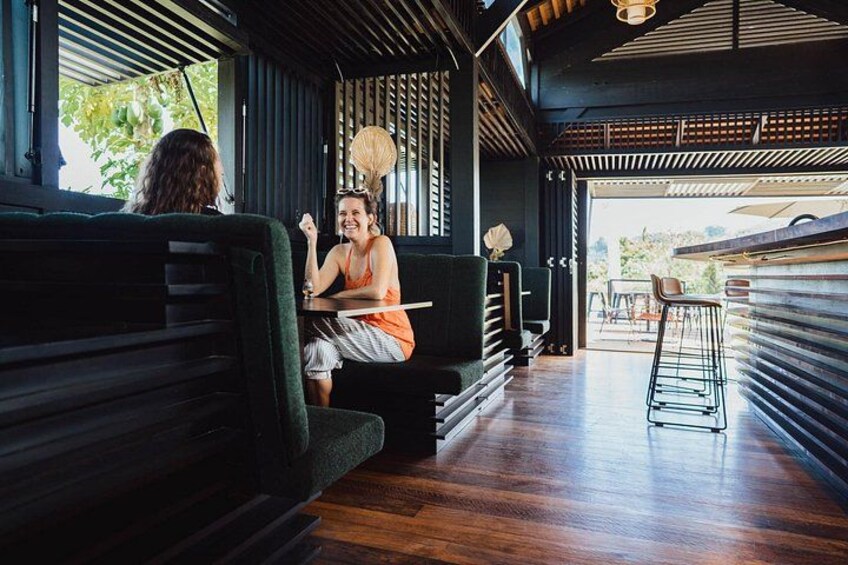 An indoor seating area with wooden flooring, a bar counter, and a view of the outdoors. 2