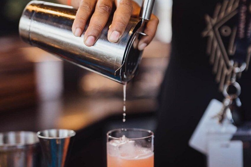 A person pouring a drink from a shaker into a glass. 4