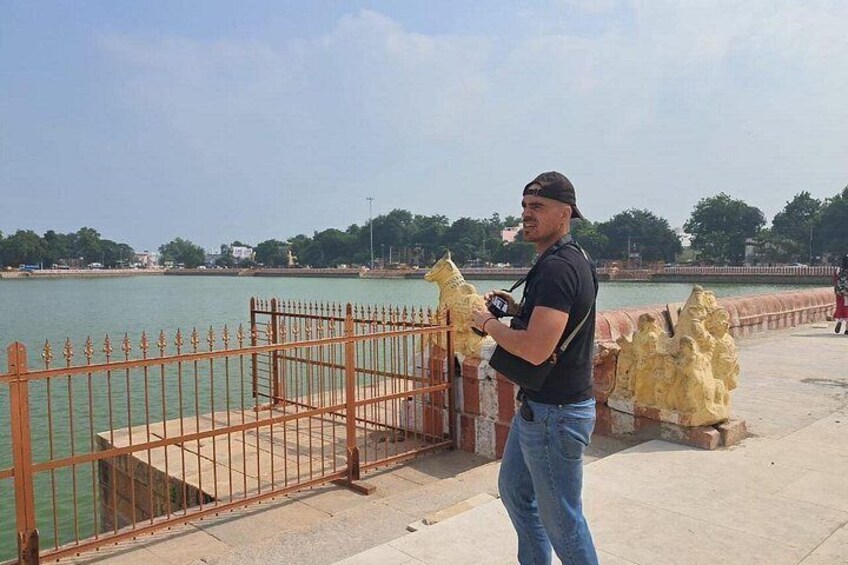 Un hombre está de pie en una pasarela de concreto junto al agua, sosteniendo una cámara. 5