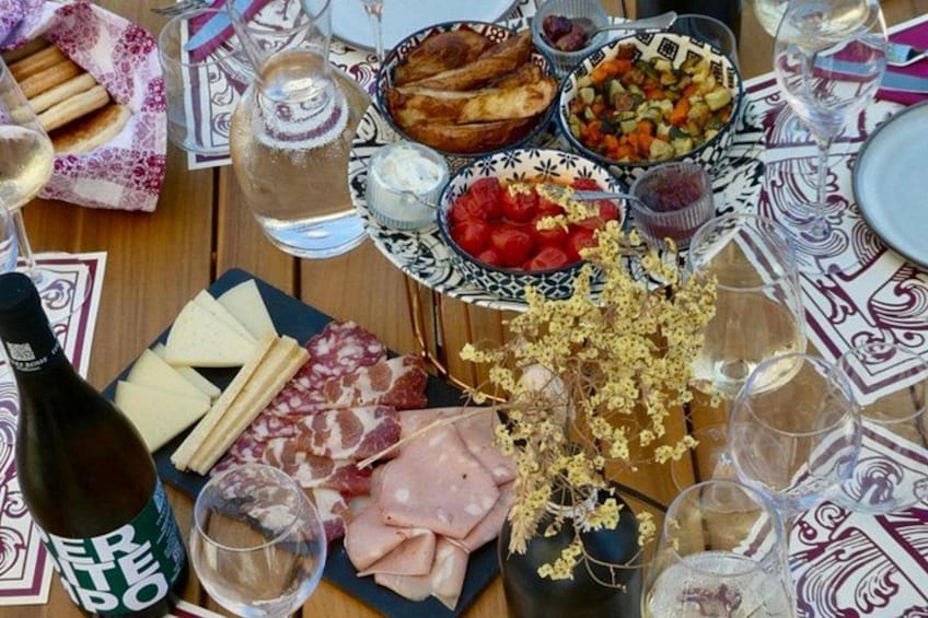 A table with various cheeses, meats, and a bottle of wine. 5