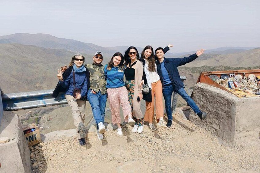 A group of people standing on a rocky outcrop with a mountainous landscape in the background. 3