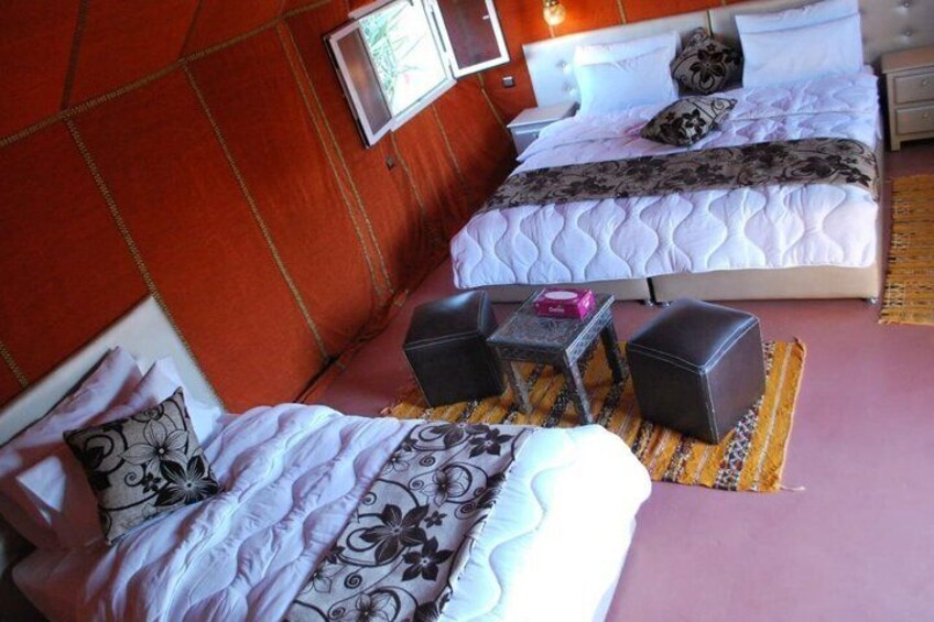 A hotel room with two beds, a small table, two chairs, and a nightstand. 5