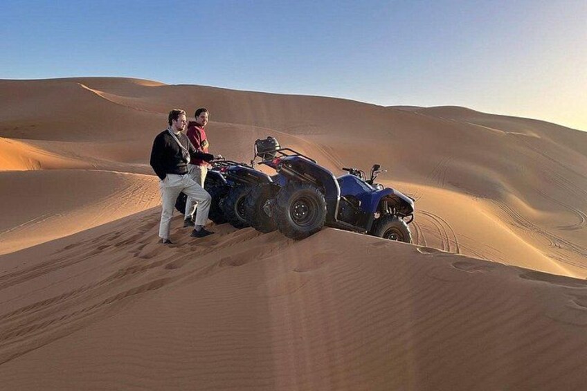 A desert landscape with sand dunes and a blue off-road vehicle. 2