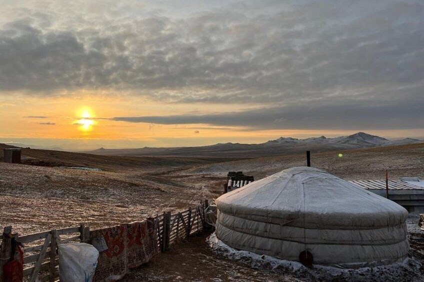 A yurt in a snowy landscape with a sunset in the background. 2