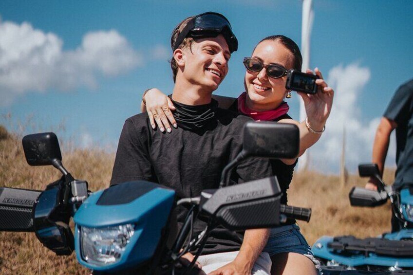 Deux personnes sur une moto bleue, dans un champ verdoyant, sous un ciel dégagé. 2