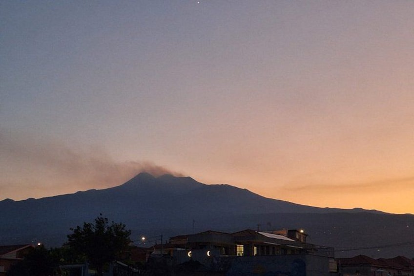 Una montaña al atardecer con un pequeño asentamiento en primer plano. 2
