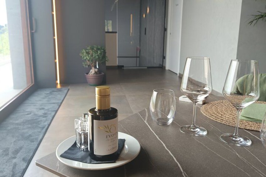 Un tavolo con una bottiglia di vino, bicchieri e un sottopiattino in un ambiente moderno. 4