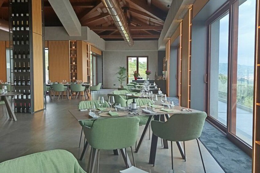 Un ristorante con sedie verdi, tavoli apparecchiati per la cena e una cantina a vista sullo sfondo. 5