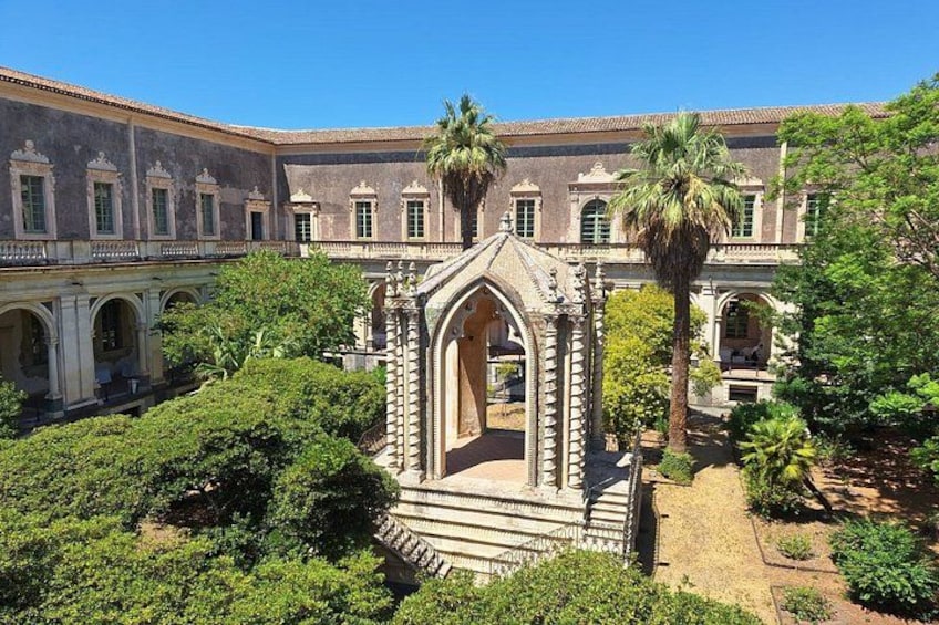 Un patio central con una fuente, rodeado de abundante vegetación y un edificio clásico con arcos. 3