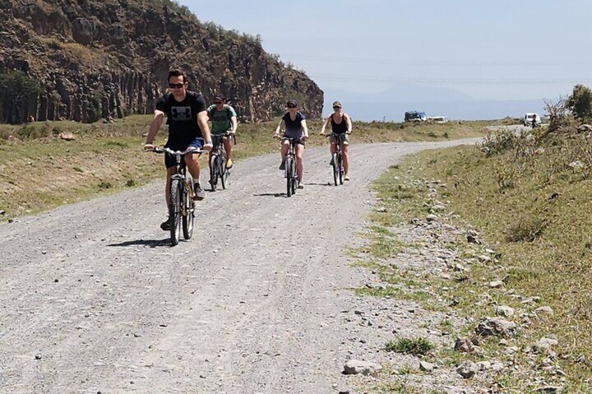 En gruppe cyklister på en grusvej med et bjergrigt landskab i baggrunden. 3