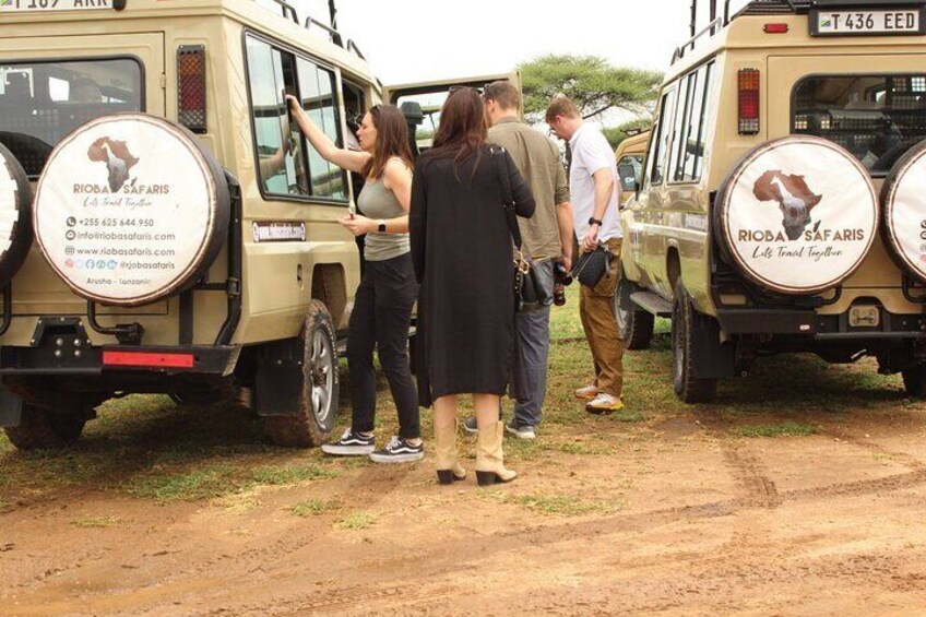 A group of people around safari vehicles with 'RIOBA SAFARIS' branding. 4