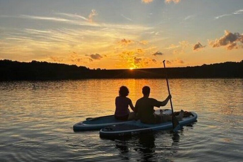 Due persone remano su una piccola barca in un lago calmo al tramonto. 4