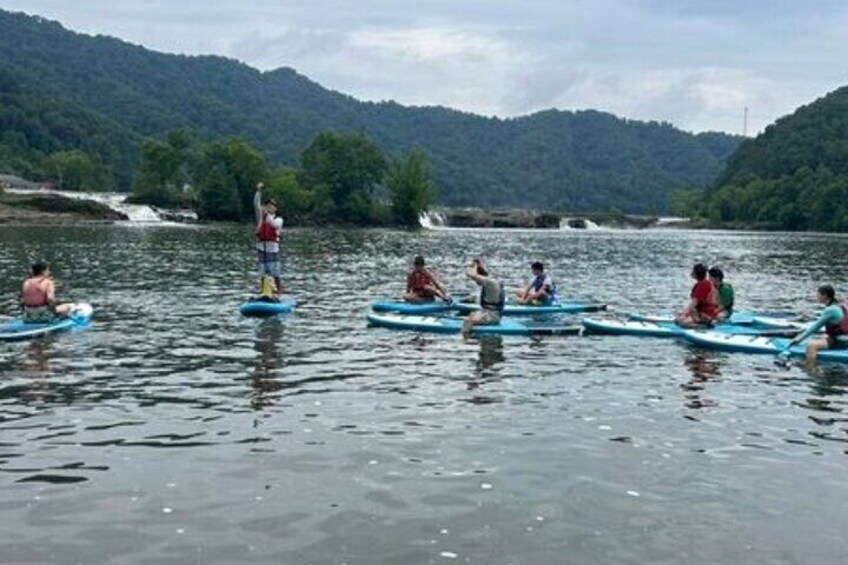 Persone che pagano con canoe su un fiume calmo, circondato da colline. 3