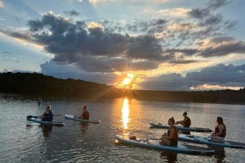 Persone che pagaiiano kayak su un lago calmo al tramonto. 2