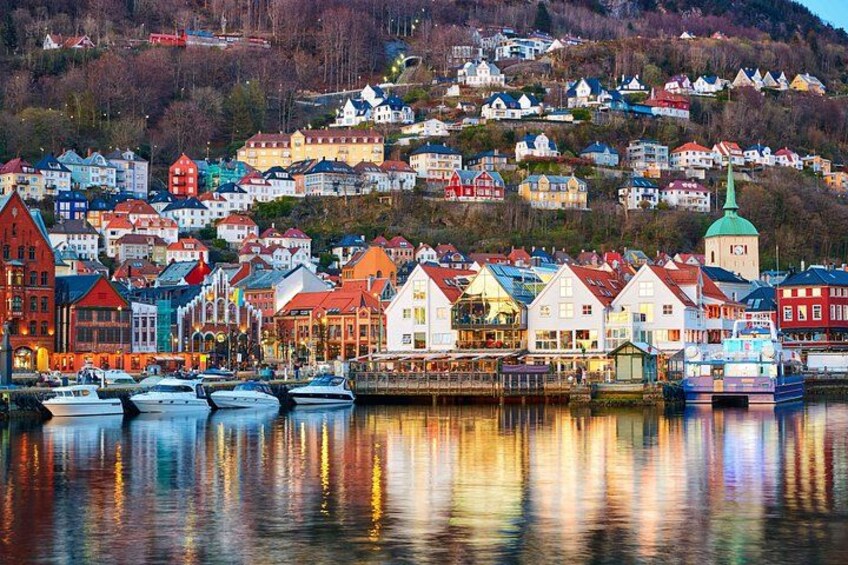A coastal town with colorful houses, boats docked in the water, and a hill with buildings in the background. 4