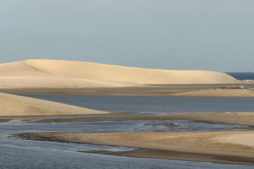 Sand dunes, a body of water, and a distant shoreline. 5
