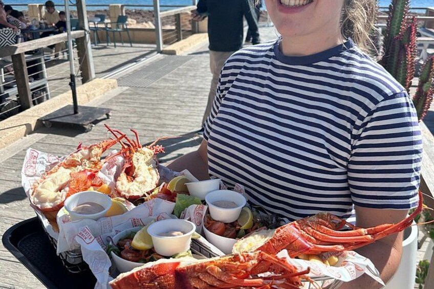 Una persona sosteniendo una bandeja con un langostino, cuñas de limón y recipientes pequeños con salsas. 2