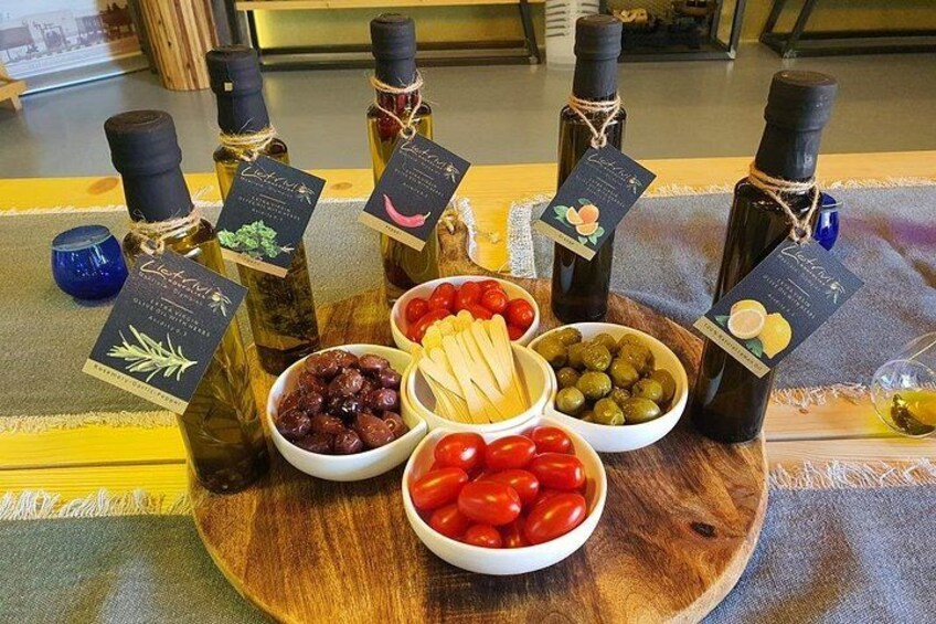 Une planche en bois sur laquelle sont disposés divers aliments et des bouteilles d’huile d’olive. 5