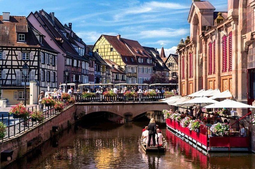 A canal with a bridge, traditional buildings, and a boat with passengers. 1
