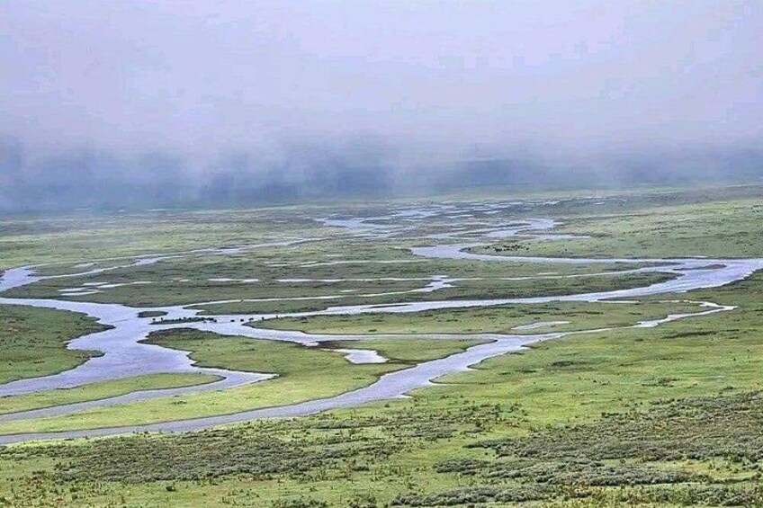 Un río serpentea a través de un paisaje verde bajo una atmósfera brumosa. 5