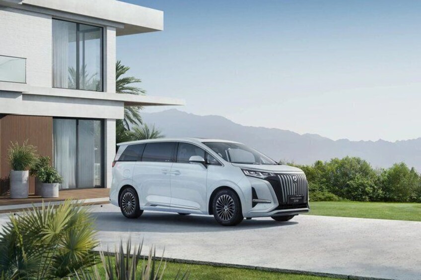 A white SUV parked in front of a modern house with a mountain backdrop. 3
