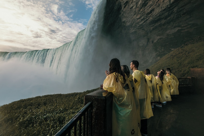 Een groep mensen in gele regenjassen die op een platform staan en een waterval bekijken. 3
