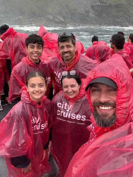 Een groep mensen draagt rode regenponcho's met de tekst 'City Cruises' en staat bij het water. 4