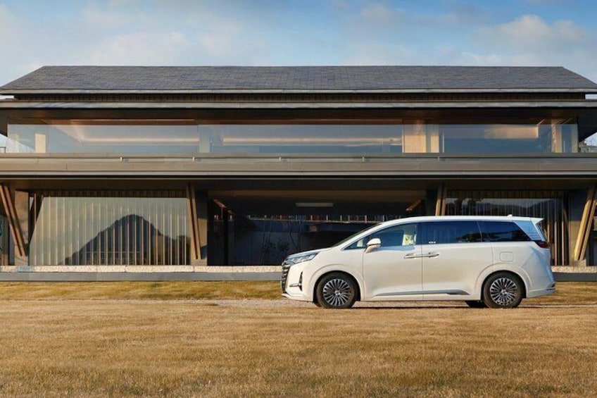 A white SUV parked in front of a modern house with a garage. 2