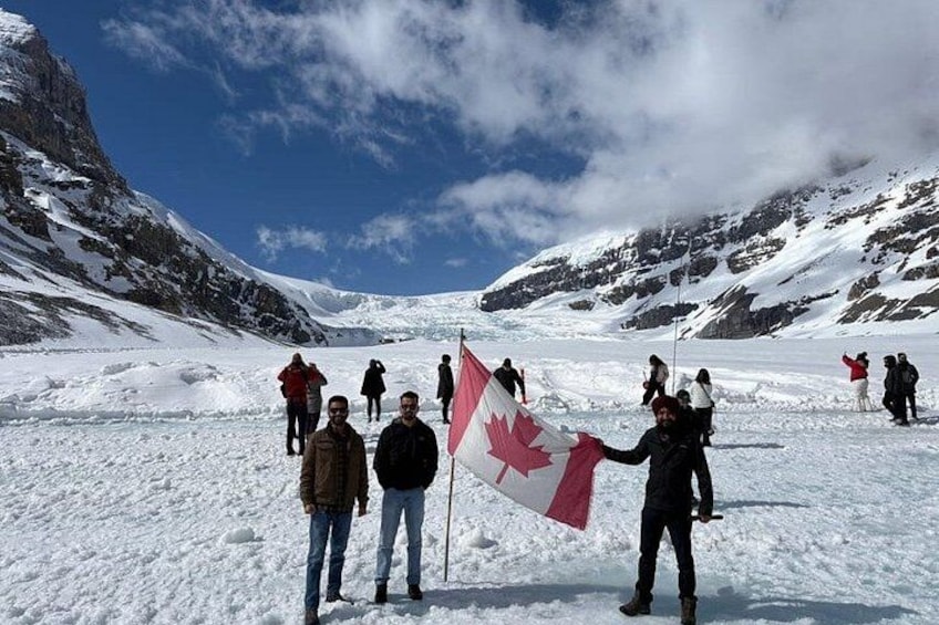 A group of people standing on a snow-covered mountain with a flag. 2