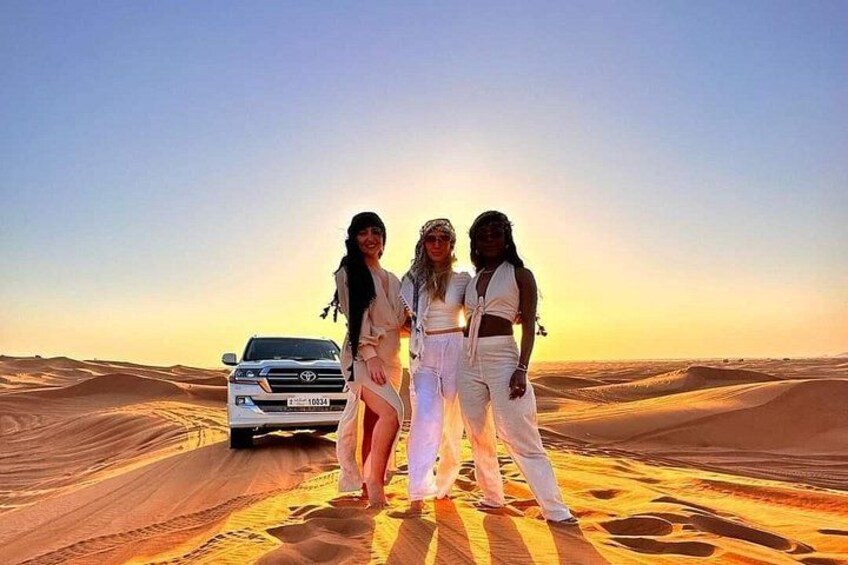 Three people standing on a desert with a white SUV in the background. 5