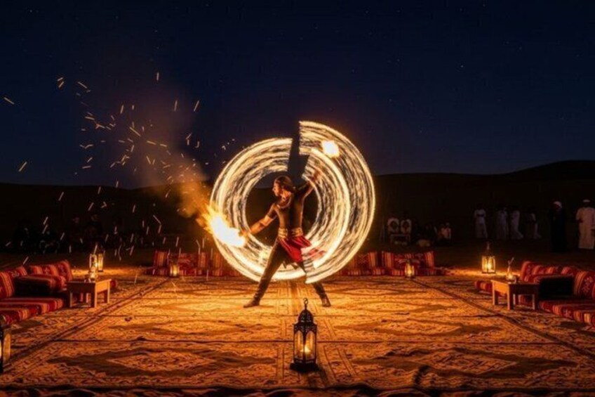 A person performing a fire act with a large fire wheel, surrounded by spectators in an outdoor setting. 3