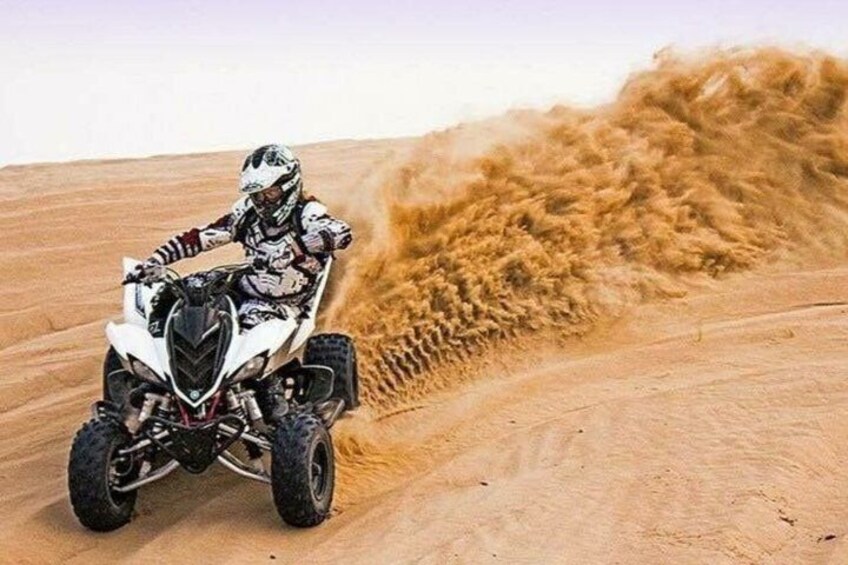 A person riding a quad bike on a sandy terrain. 5