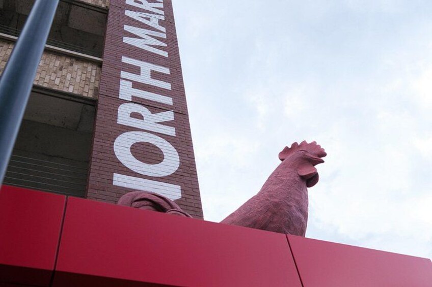 A large red building with a prominent sign reading 'NORTH MARKET' and a large pink rooster sculpture on top. 2
