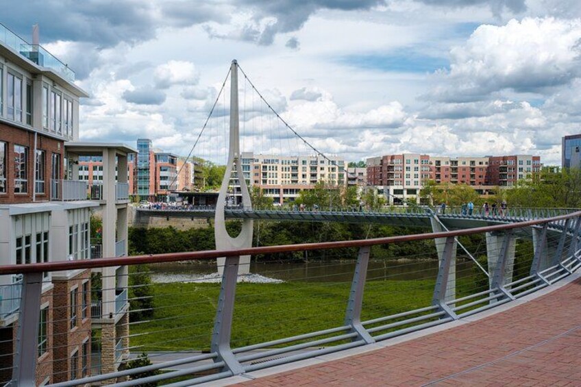 A modern bridge with a unique design, a river below, and buildings in the background. 1