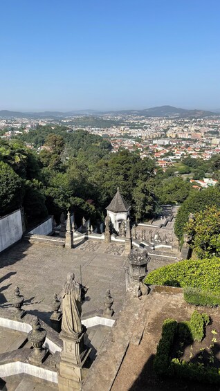 Un sitio histórico con estatuas y un pequeño pabellón, con vistas a un paisaje urbano y montañas a lo lejos. 3