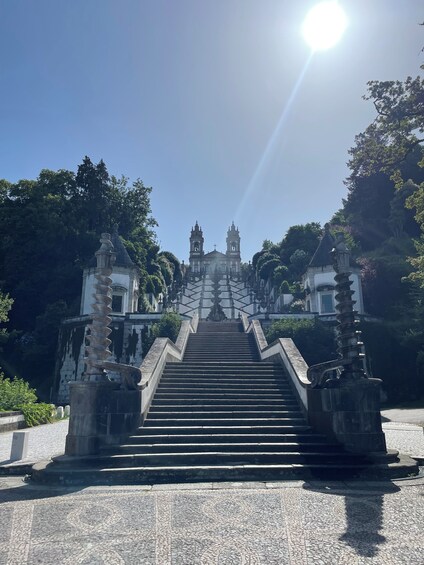 Una imponente escalera conduce a un edificio histórico con dos torres de campanas, rodeado de exuberante vegetación. 4