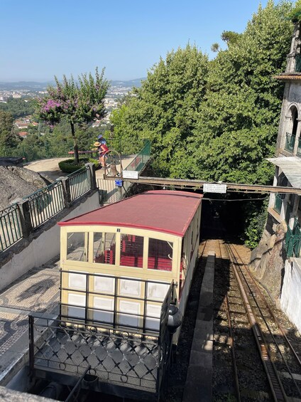 Un tranvía antiguo sobre rieles, un puente de piedra y una vista de la ciudad con árboles y una estatua. 2