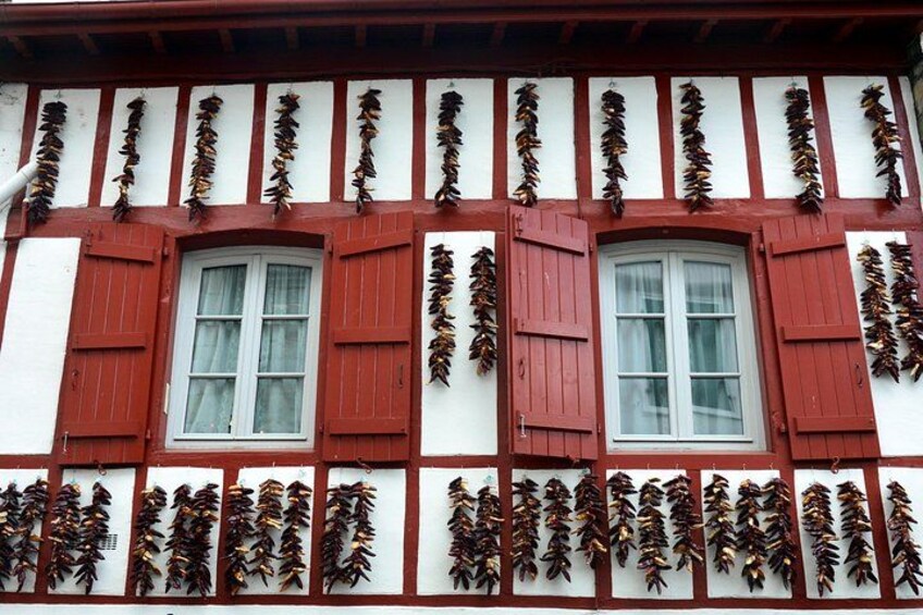 A half-timbered building with red shutters and decorative leaf garlands. 2