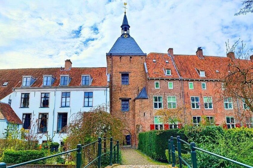 A historic building with a tower, surrounded by traditional houses and a well-maintained garden. 3