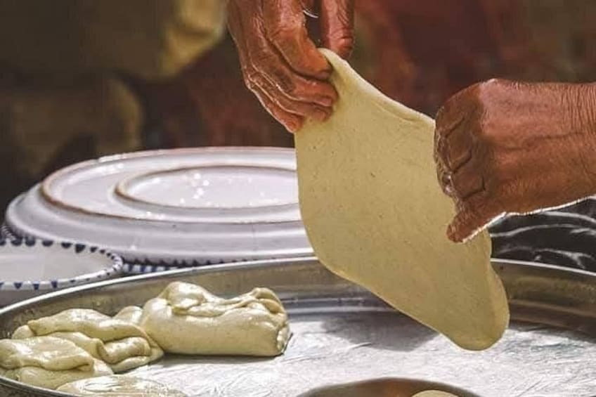 A person stretching dough on a metal surface. 3