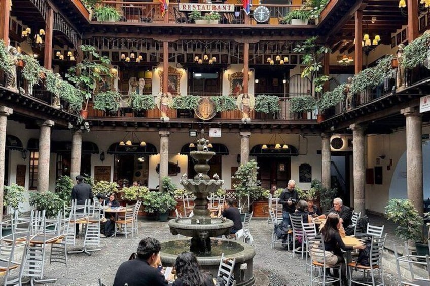 A courtyard with a fountain, tables, chairs, and potted plants. 5