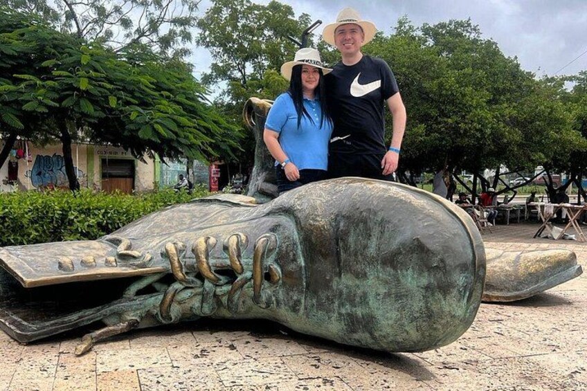 A large sculpture of a shoe with laces, a person in a blue shirt, and another in a black shirt with a Nike logo. 5