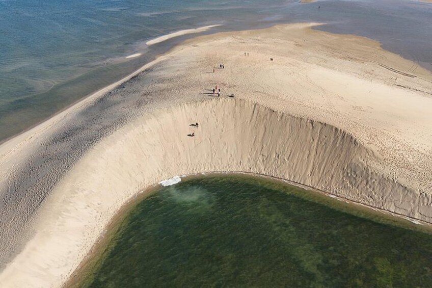 A large, deep sinkhole surrounded by a sandy beach and clear water. 5