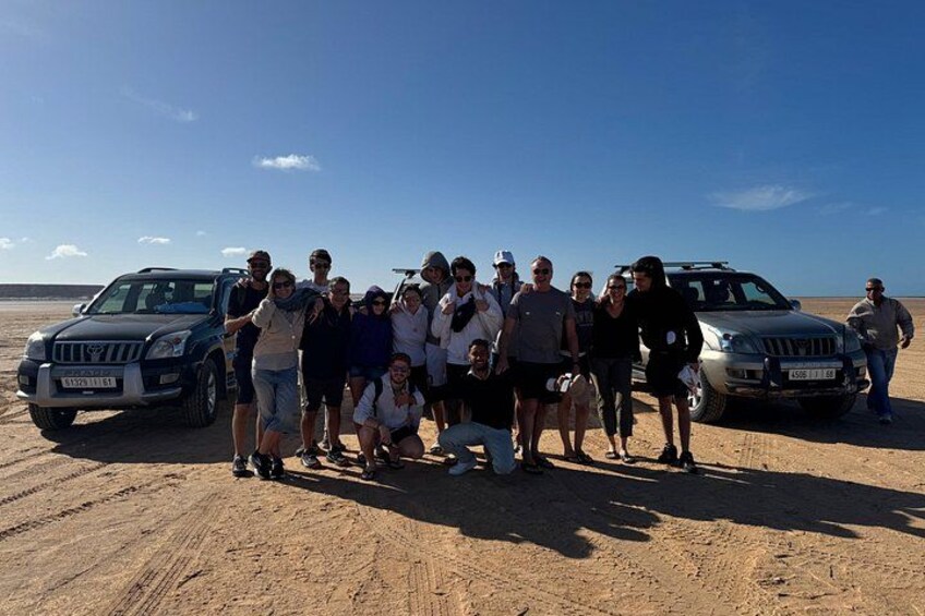 En gruppe mennesker poserer i et ørkenlandskab med to jeeps. 3