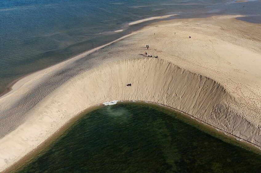 A large sand dune with a small water body at its base. 3